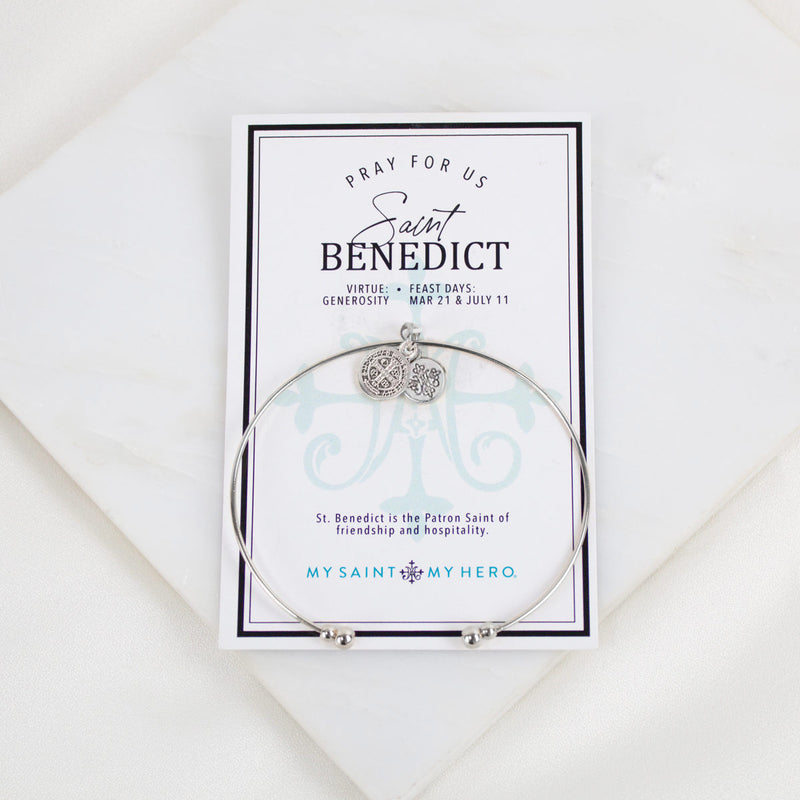 Silver-tone Saint Benedict Medal Whisper Bangle Cuff bracelet displayed on its inspirational 'Pray For Us' saint card.