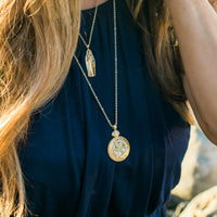 close up of a woman wearing a St. Mary Magdalene Necklace in gold tone with white enamel rosette