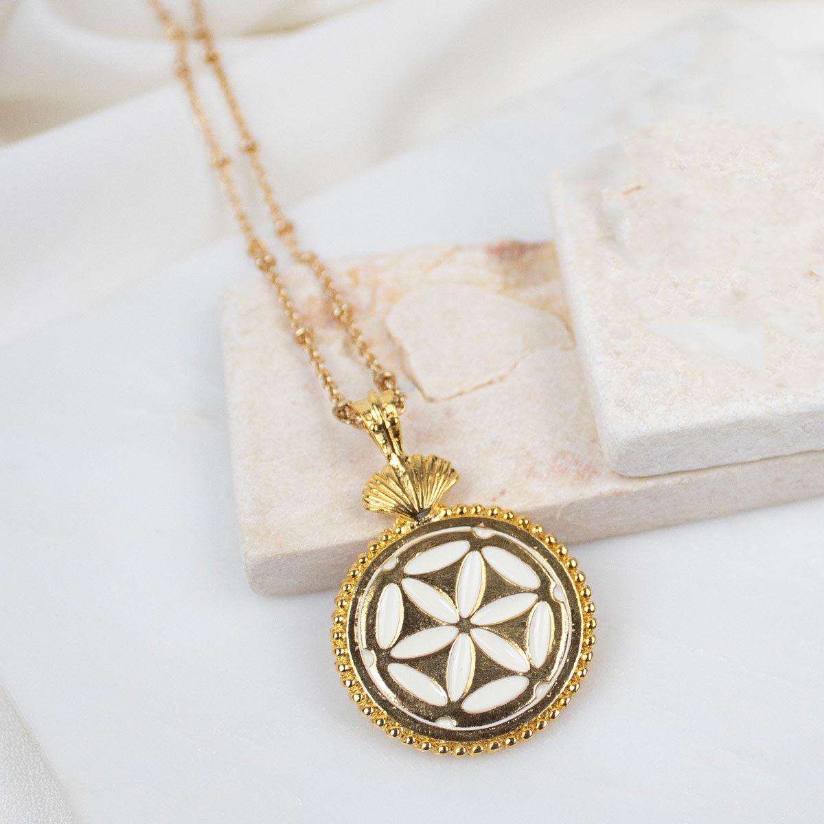 Gold St. Mary Magdalene Necklace with a decorative pendant on a marble surface