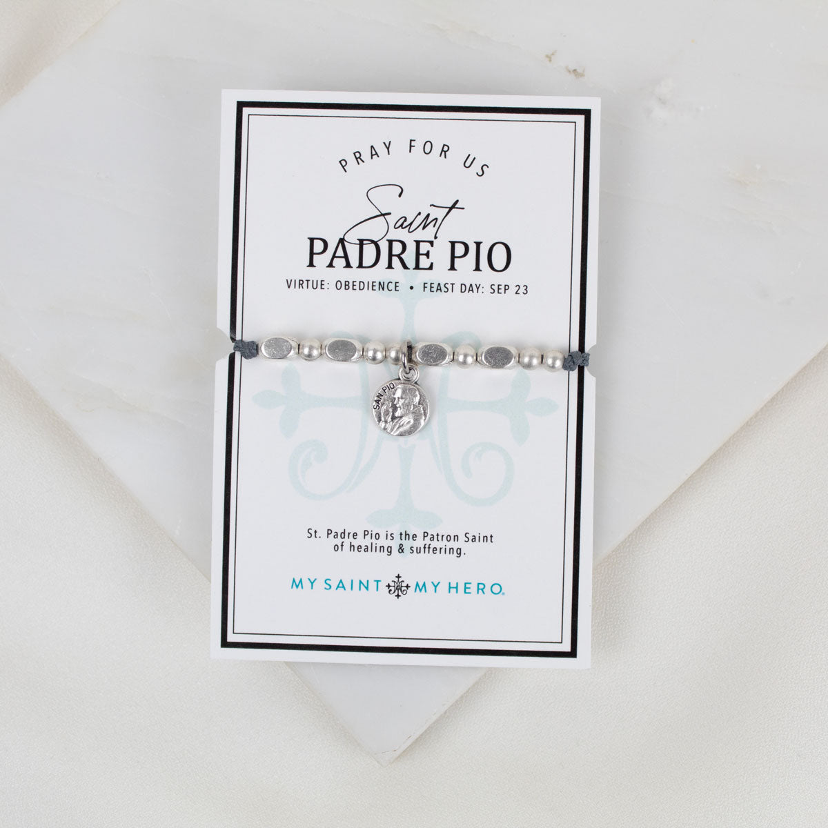 An image of the Saint Padre Pio Little Saints Bracelet with silver-tone metal beads and a Saint Padre Pio medal, presented on a card with information about the saint and the bracelet's purpose.