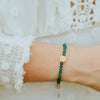close up of green crystal and gold benedictine medal bracelet on wrist