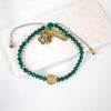 overhead shot of emerald green crystal and gold tone blessed tag and st. benedict  medal bracelet