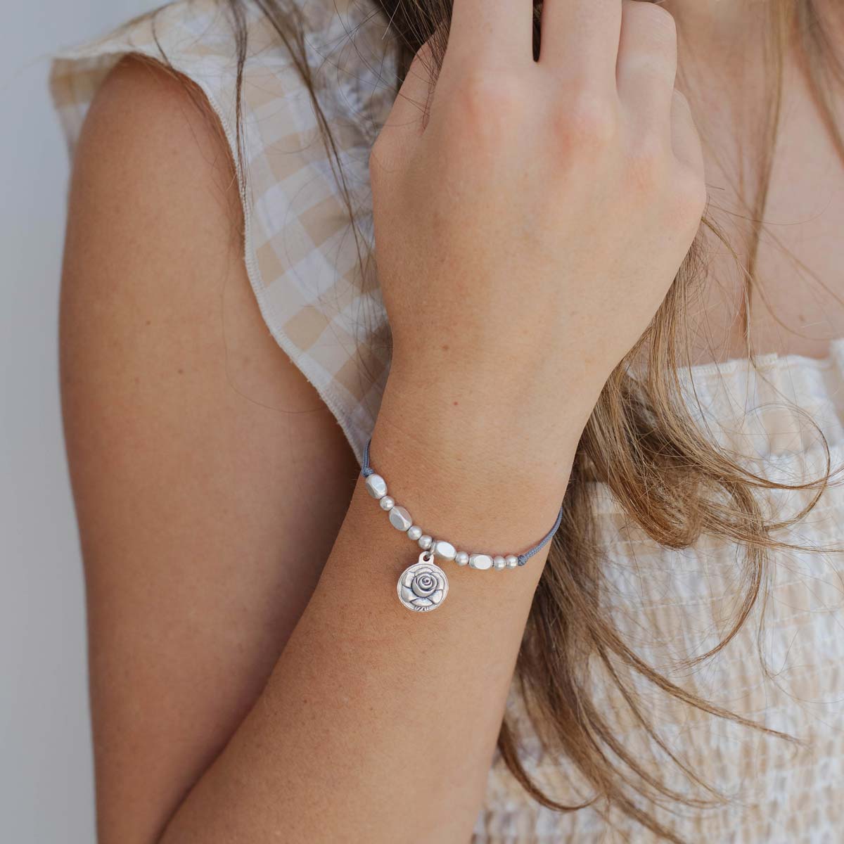 Person wearing a St. Thérèse of Lisieux bracelet with a rose  saint medal charm 