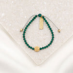 overhead shot of emerald green crystal and gold tone blessed tag and st. benedict  medal bracelet