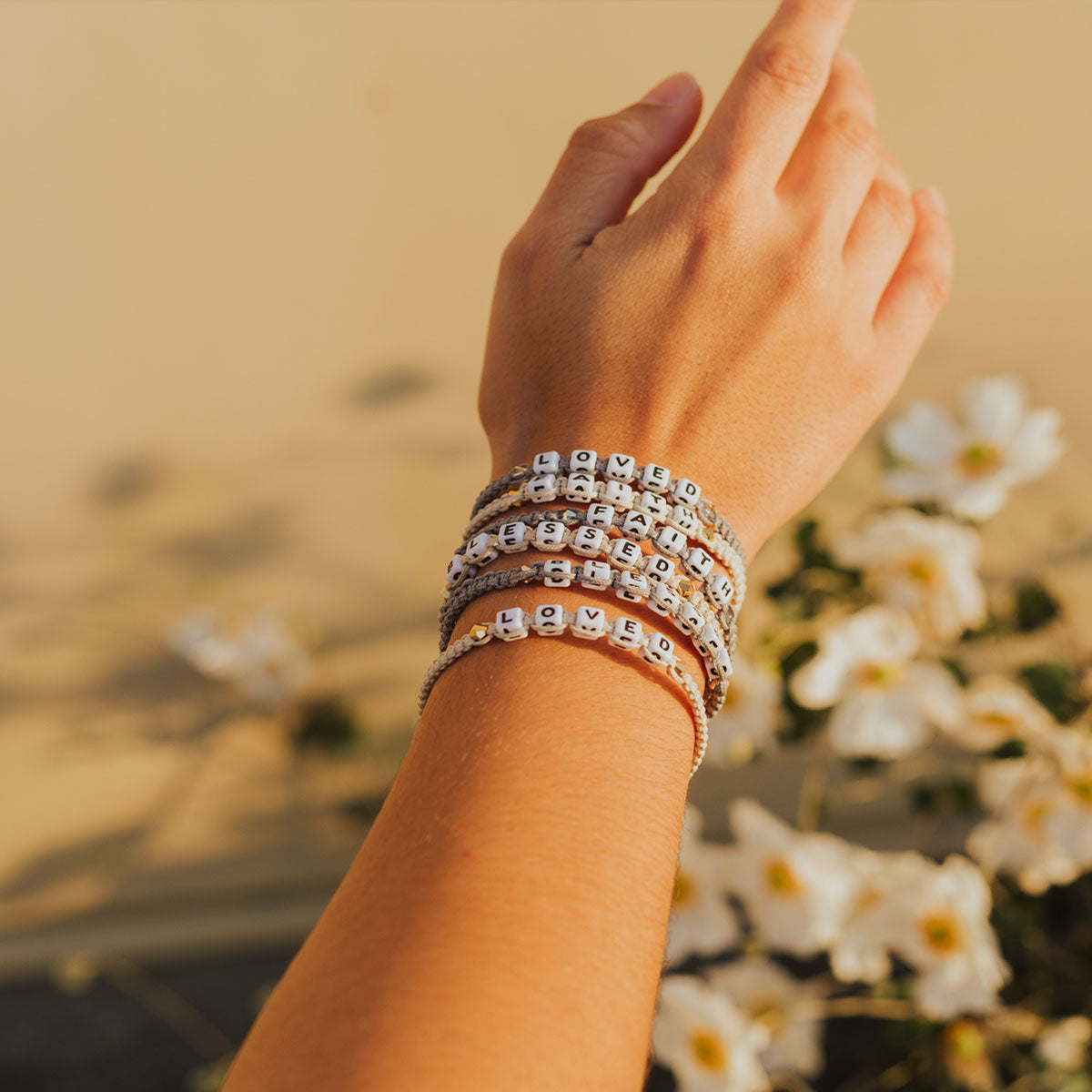 woman wearing the Little Words Project and My Saint My Hero Loved Bracelet and other bracelets from the collection