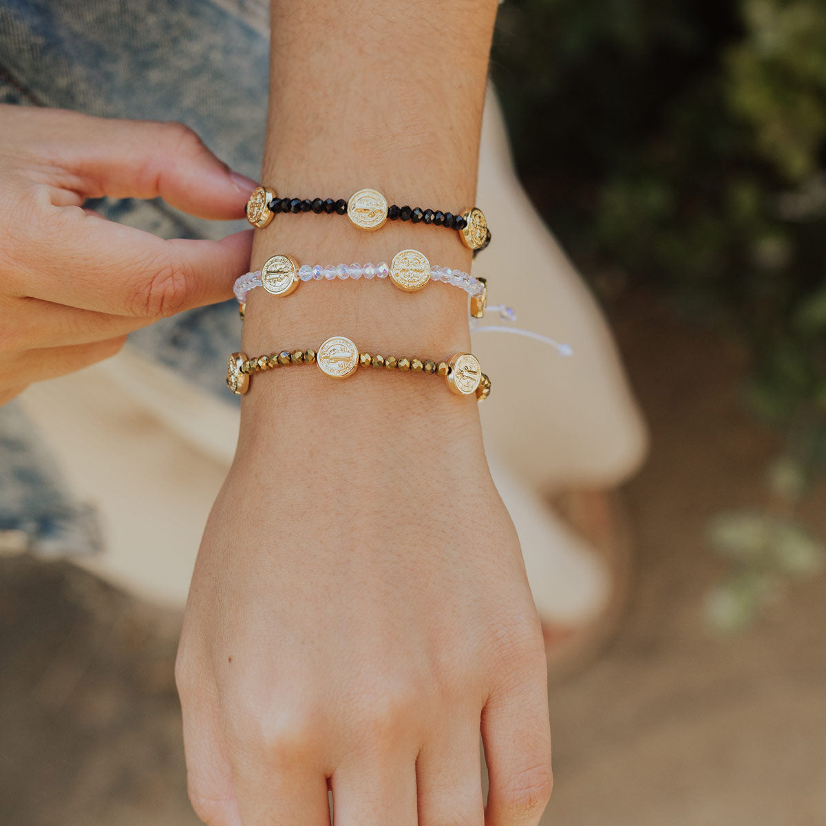 Close-up of a wrist wearing multiple beaded bracelets with a blurred natural background
