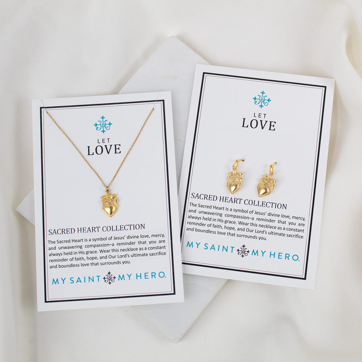 Two gold necklaces on cards with 'My Saint My Hero' branding on a white background