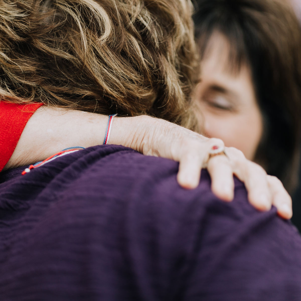 Close-up of a person's hand on another person's shoulder, with a blurred background