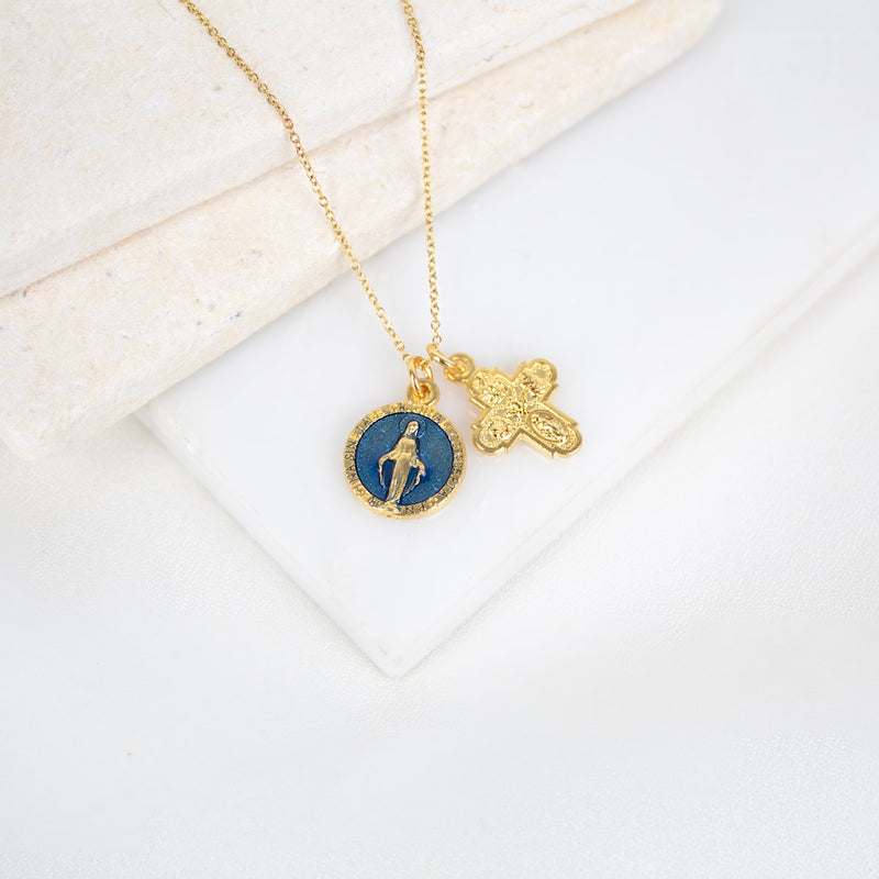Gold necklace with a blue pendant and cross on a white surface