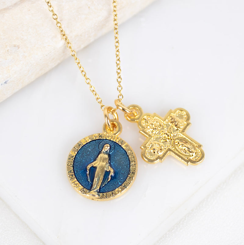 Gold necklace with a blue pendant and cross on a white surface
