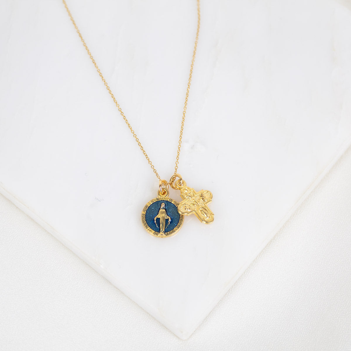 Gold necklace with two charms on a white background