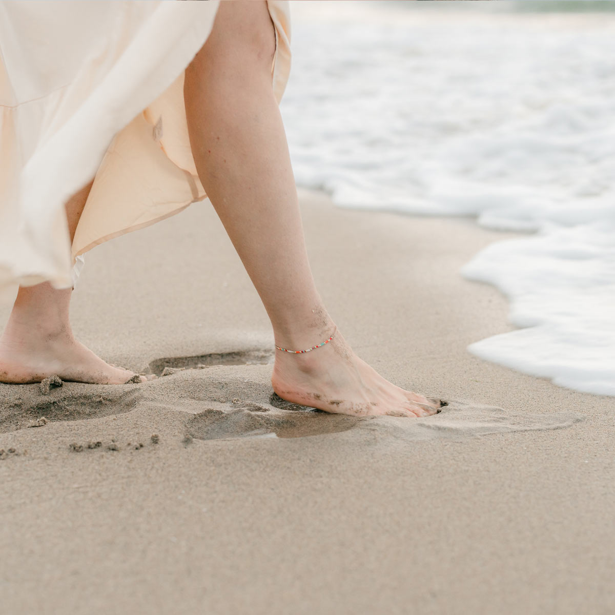 woman walking in the sand wearing a Walk by Faith Anklet