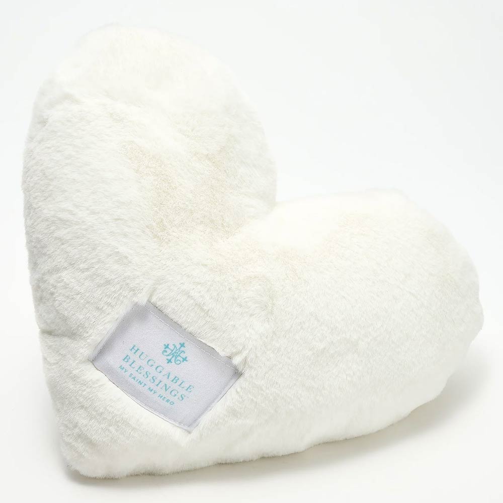 A plush, white weighted pillow in the shape of a heart with a label that reads 'Huggable Blessings'.