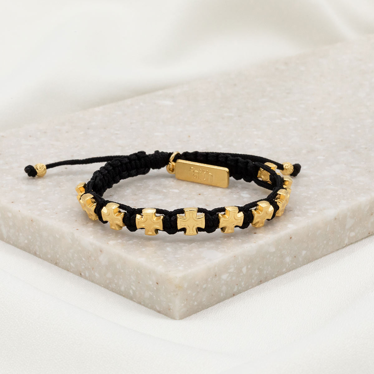 ten gold tone cross medals and a faith tag on handwoven black cording
