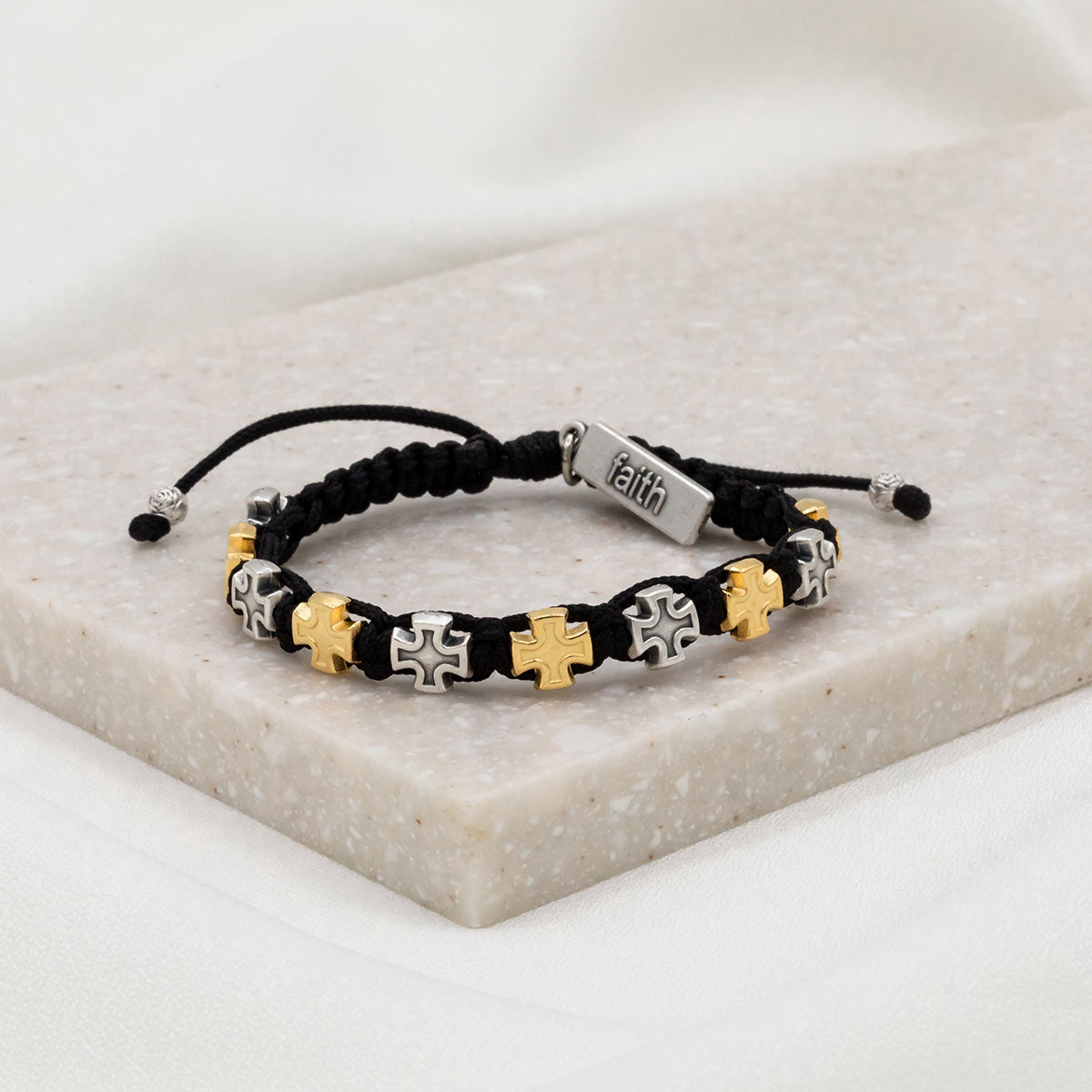 alternating gold and silver tone cross medals on black cording with a silver tone faith tag at slip knot