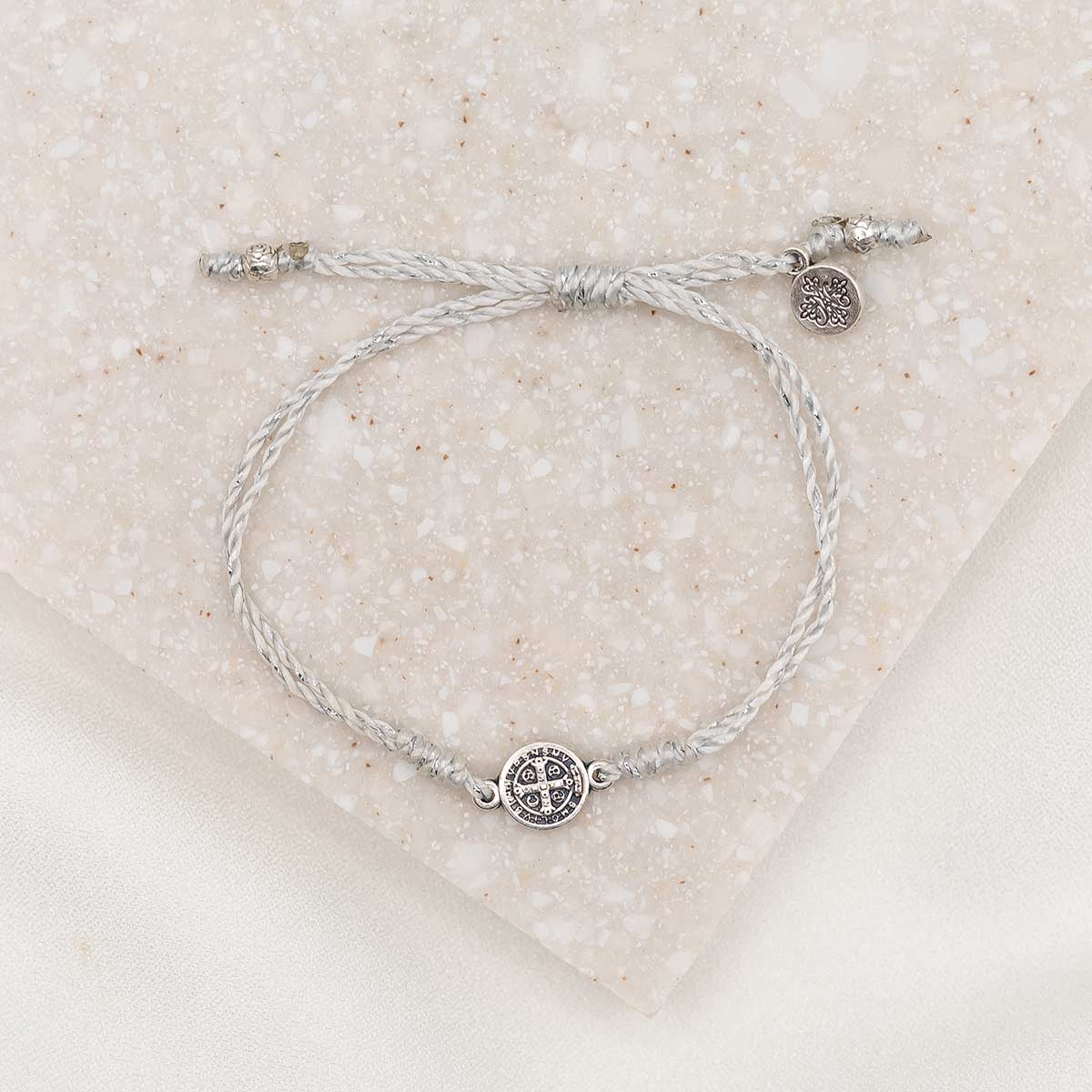 silver-tone St. Benedict medal on silver metallic bracelet cording 