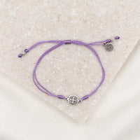 silver-tone St. Benedict medal on lavender bracelet cording with a slipknot closure