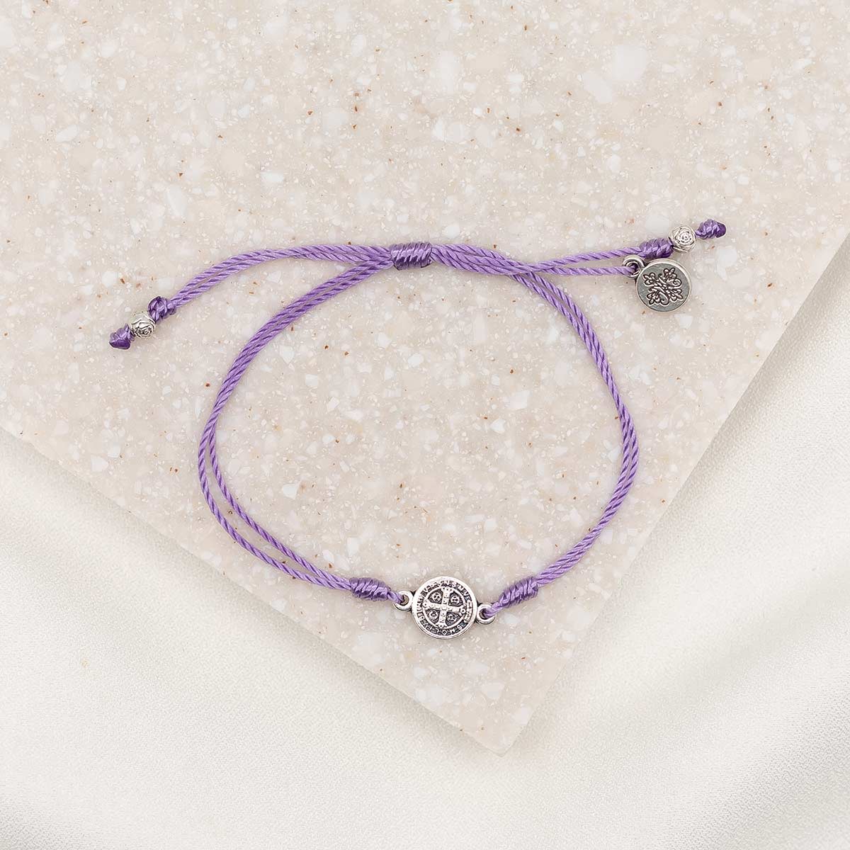 silver-tone St. Benedict medal on lavender bracelet cording with a slipknot closure