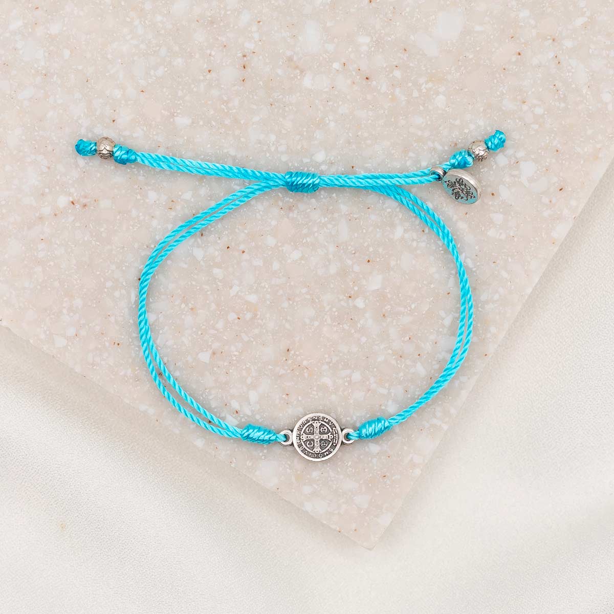 silver-tone St. Benedict medal on turquoise bracelet cording with a slipknot closure