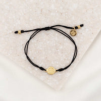 gold-tone St. Benedict medal on black bracelet cording with a slipknot closure