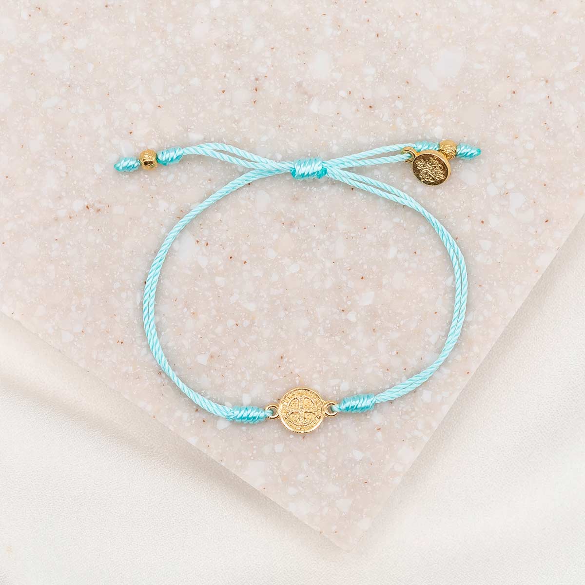 gold-tone St. Benedict medal on mint bracelet cording with a slipknot closure