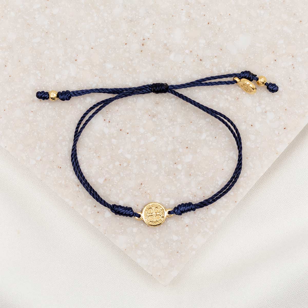 gold-tone St. Benedict medal on navy bracelet cording with a slipknot closure