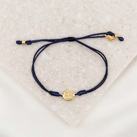gold-tone St. Benedict medal on navy bracelet cording with a slipknot closure