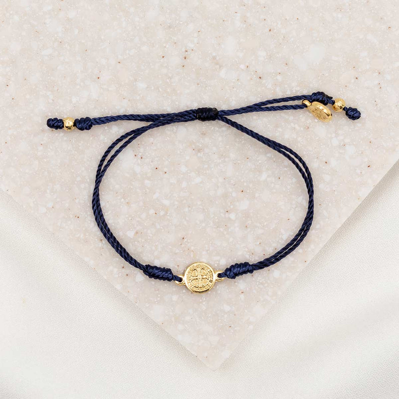 gold-tone St. Benedict medal on navy bracelet cording with a slipknot closure
