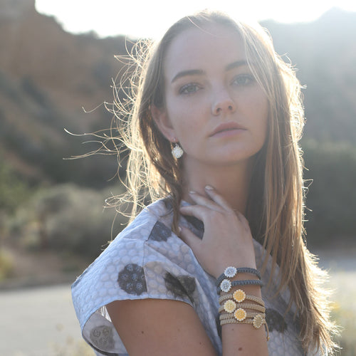 Blonde girl in mountains wearing Brilliance Blessing Bracelets in slate and cream cording