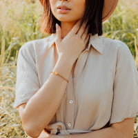 Young woman in field wearing a Shine Bright Crystal Blessing Bracelets in gold crystal and gold tone St. Benedict Medal