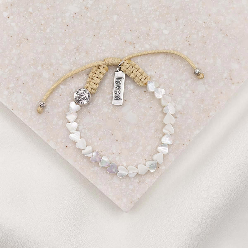 mother of pearl heart bracelet on tan woven cording with silver loved charm tag and silver blessed medal bead