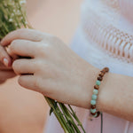 Wood and amazonite bracelet on a woman's hand holding flowers