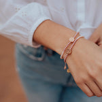 close up of woman's arm wearing two Love Lights the Way crystal pearl pink ombre bracelets