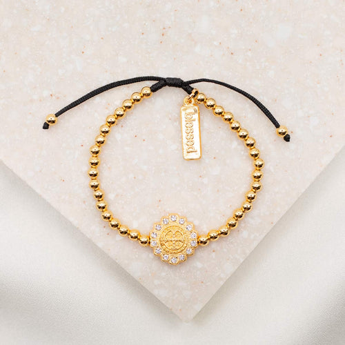 Mantra of Beauty & Brilliance Bracelet gold tone Benedictine Medal surrounded by crystals with gold tone beads on black woven slip know bracelet cording