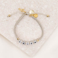 Little Words Project and My Saint My Hero Faith Bracelet over head of gold version showing cross and logo charms