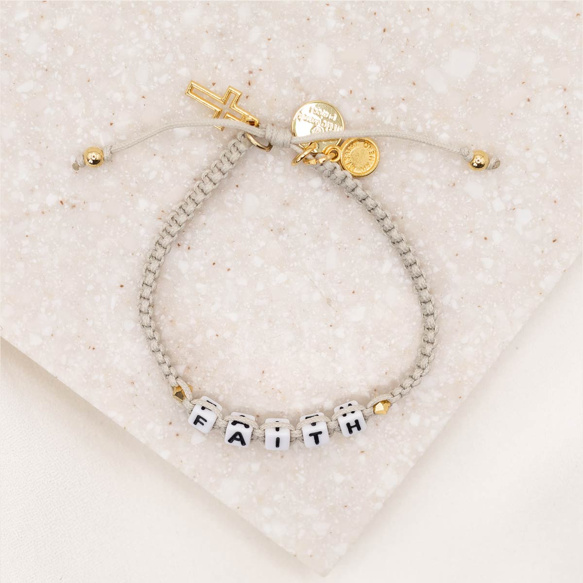 Little Words Project and My Saint My Hero Faith Bracelet over head of gold version showing cross and logo charms