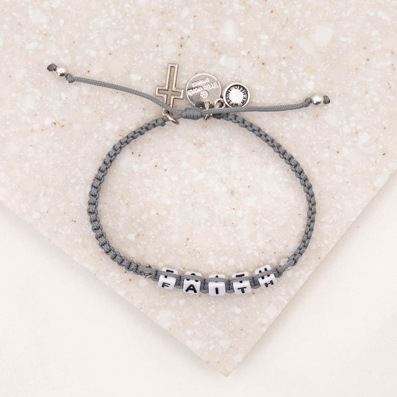 over head shot of Little Words Project and My Saint My Hero Faith Bracelet showing cross and logo charms