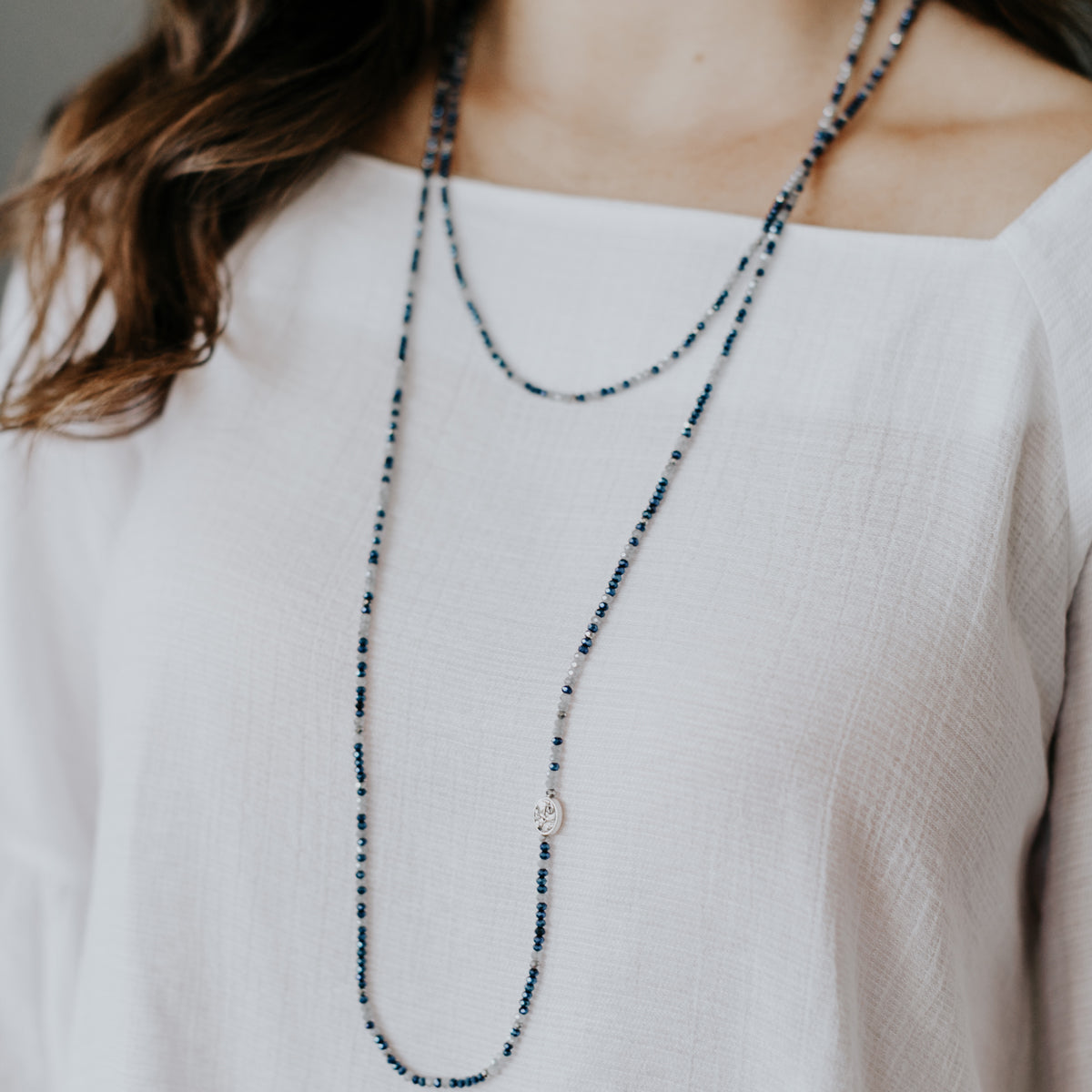 Close up of a woman wearing the Prayer Rope doubled on a white shirt