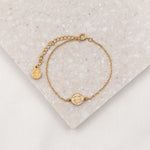 dainty st. Benedict gold tone chain braclet with two inch larger chain extender and small round my saint my hero cross logo charm shot overhead on white background