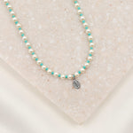 Crystal Pearl and turquoise beaded necklace with petite Miraculous Medal in sterling silver on marble slab