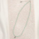 Crystal Pearl and turquoise beaded necklace with petite Miraculous Medal in sterling silver on marble slab overhead