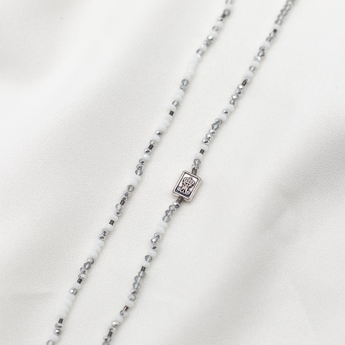 close up of the Auspice Maria Medal silver tone on silver and white beaded prayer rope