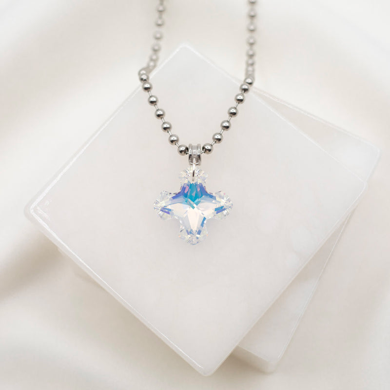 A silver-colored cross necklace with a large, clear, square-shaped crystal pendant, displayed against a white background.