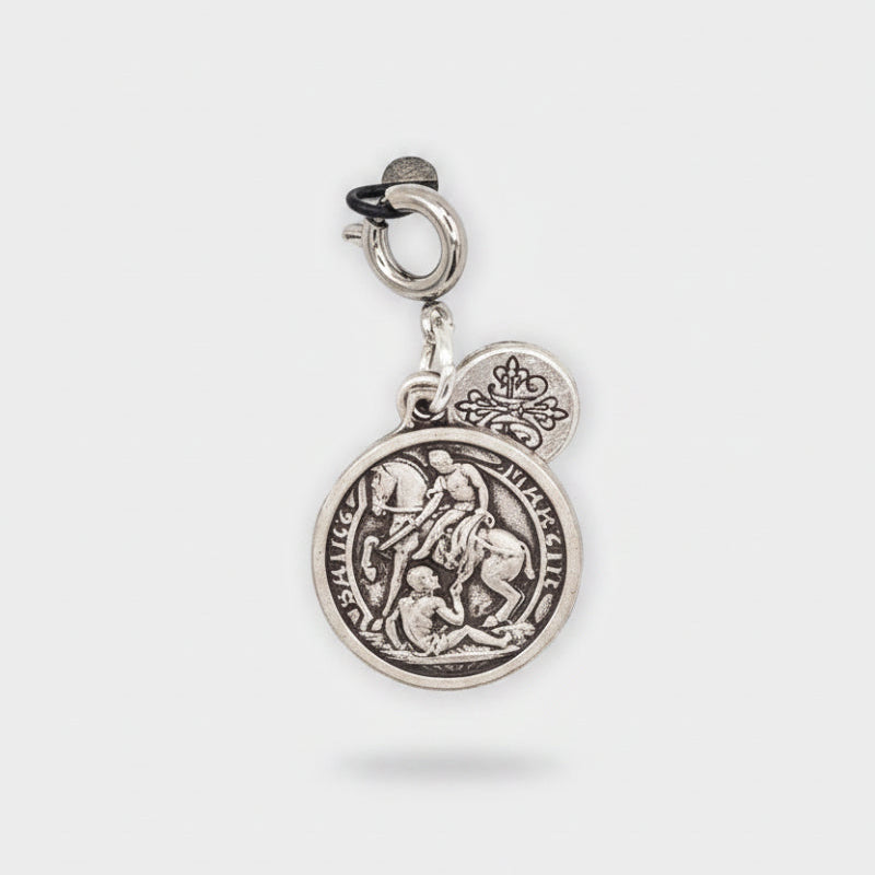 A silver St. Martin de Tour's medal charm with a crown emblem, featuring an engraved saint design and a lobster clasp, shown on a light gray background.