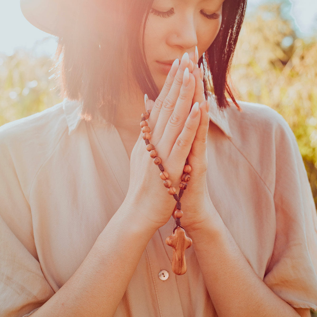 Young woman praying with the Holy Land Olive Wood and Cross Peace Prayer Chaplet'
