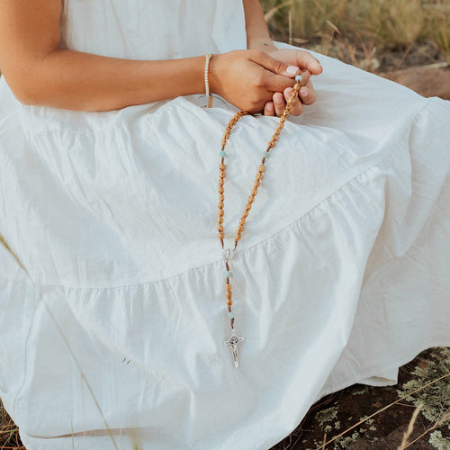 Olive Wood and Amazonite Medjugorje Rosary held by young person in field in white dress