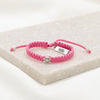 pink cording woven slip knot bracelet with silver tone medal and silver tone faith tag