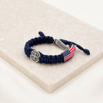 Navy handwoven blessing bracelet with silver-tone St. Benedict Medal and blessed charm tag and American Flag 