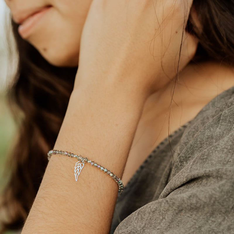 dainty crystal beaded bracelet with angel wing in silver tone on woman's wrist
