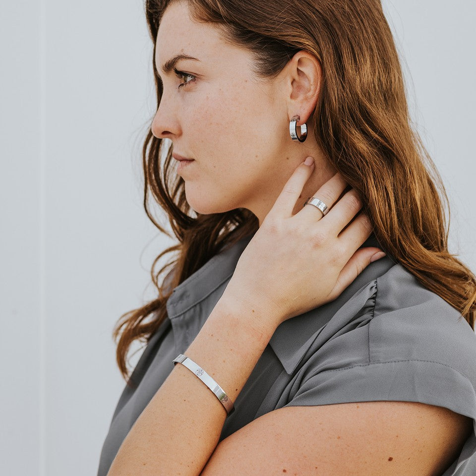 Young brunette woman wearing The Greatest Love Deuteronomy earrings, ring, bracelet bangle in silver